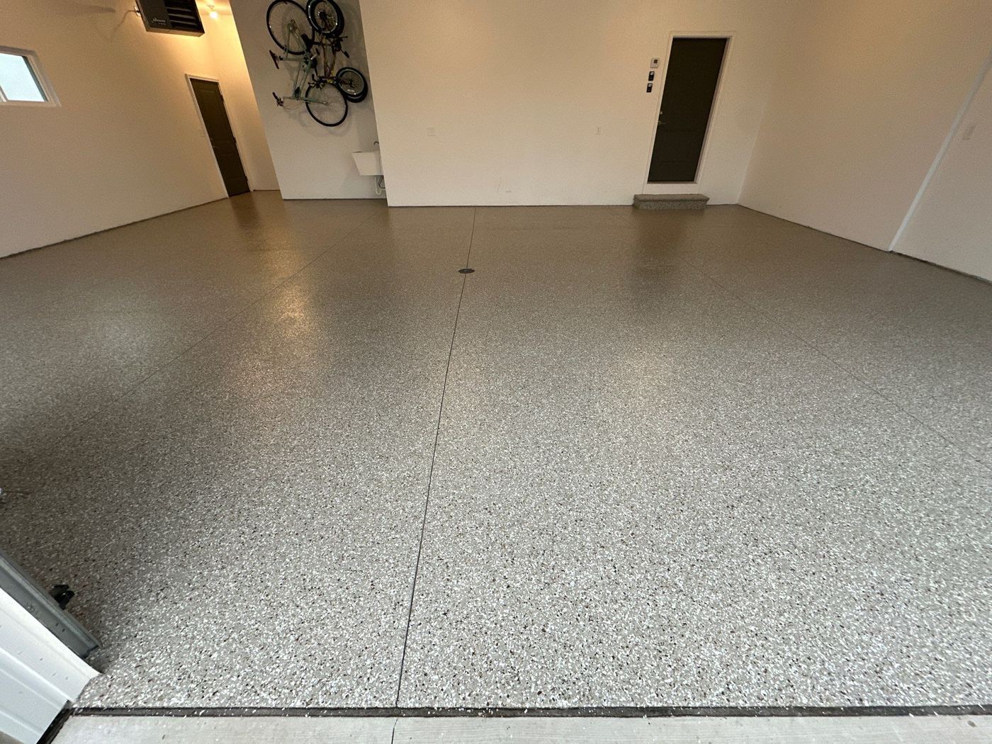 Large garage floor with Penntek polyurea tan flake coating — high-gloss nighttime shot